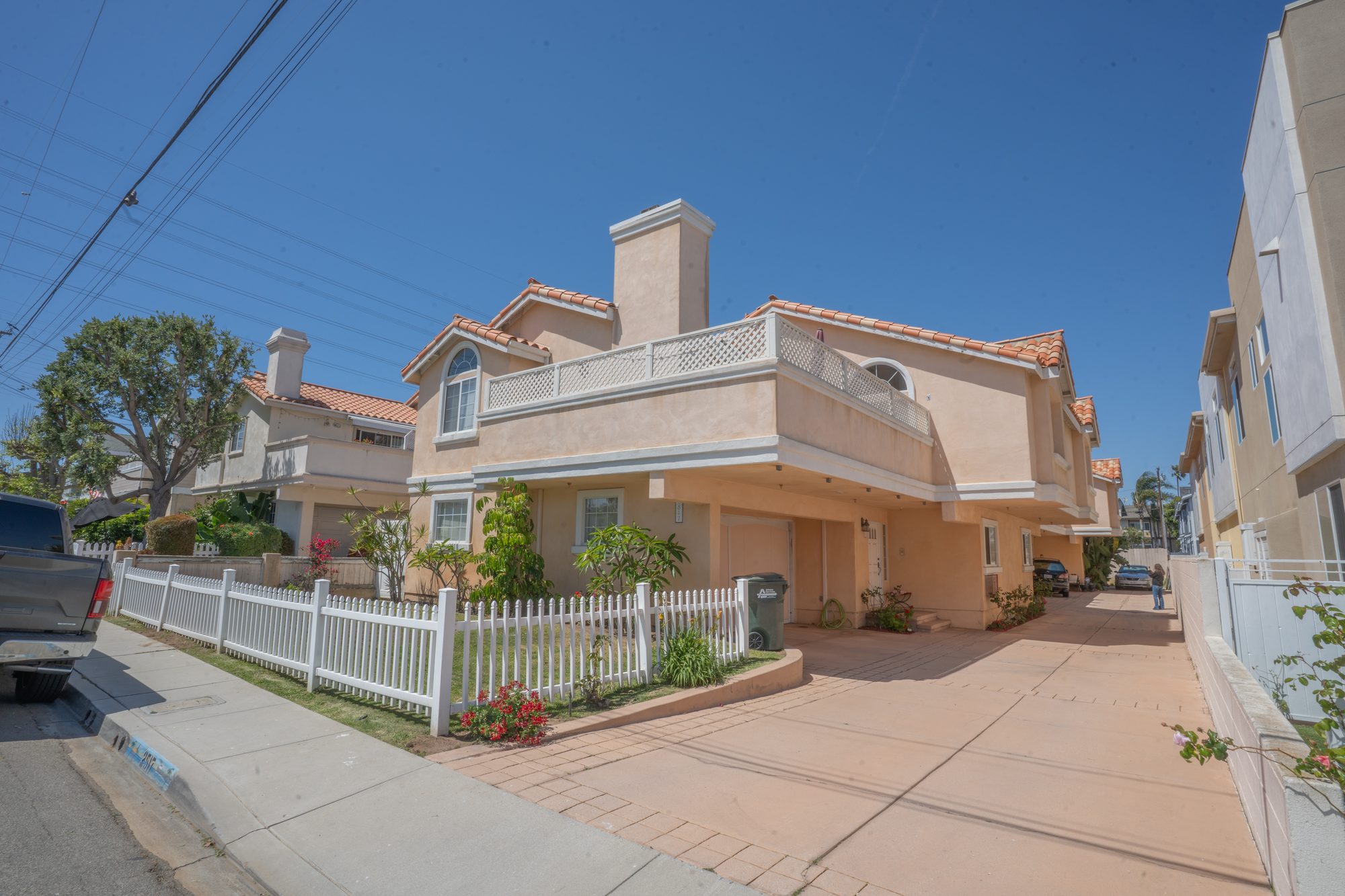Front exterior of the townhome with white picket fence and tile roof