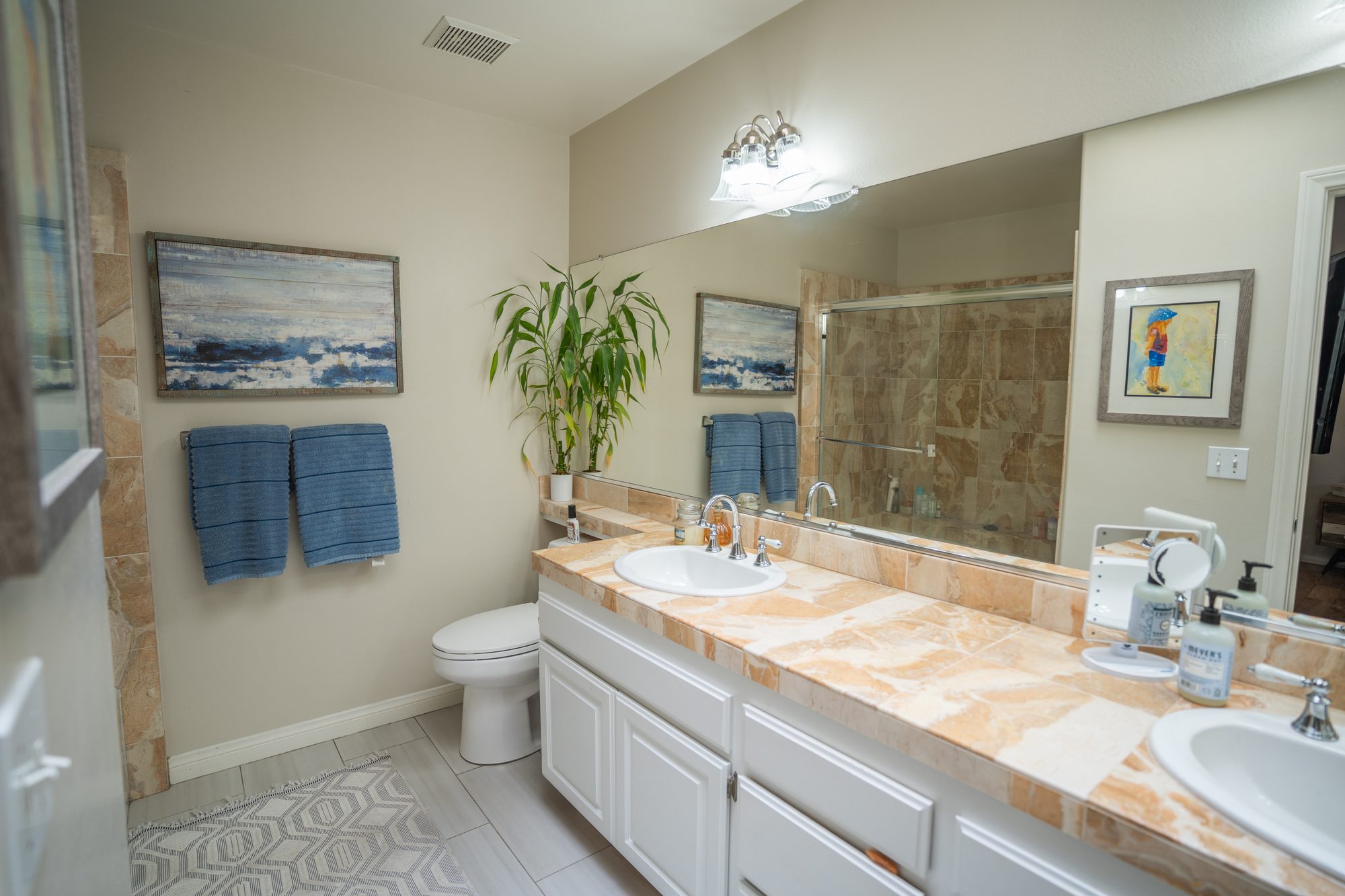 Primary bathroom with dual-sink vanity and travertine countertops